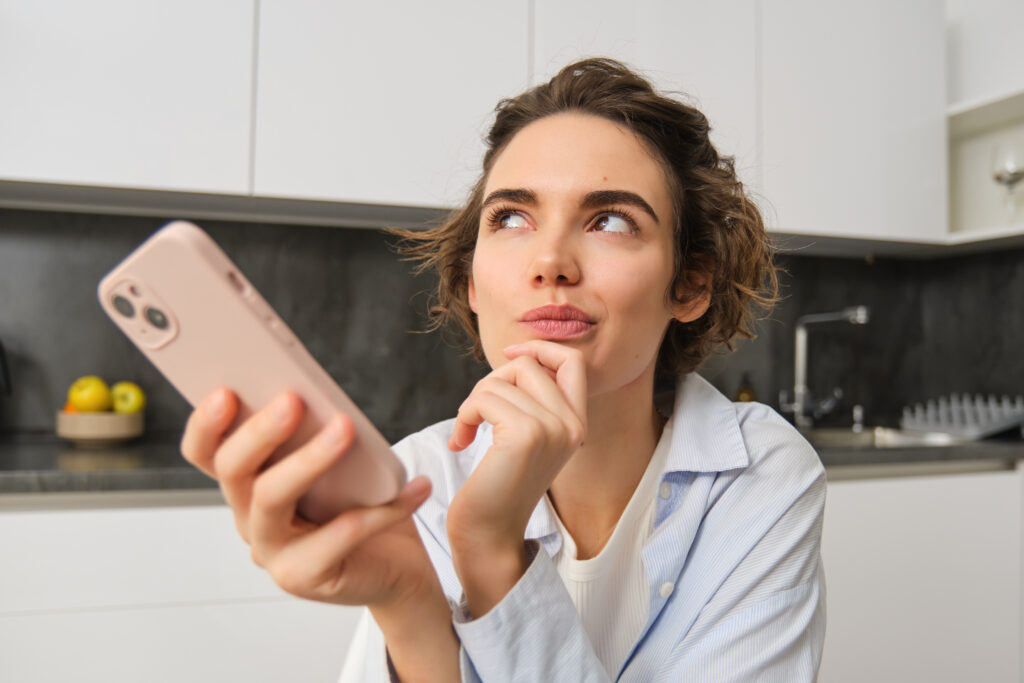 Portrait of woman at home, holding smartphone, digital planning strategy social media